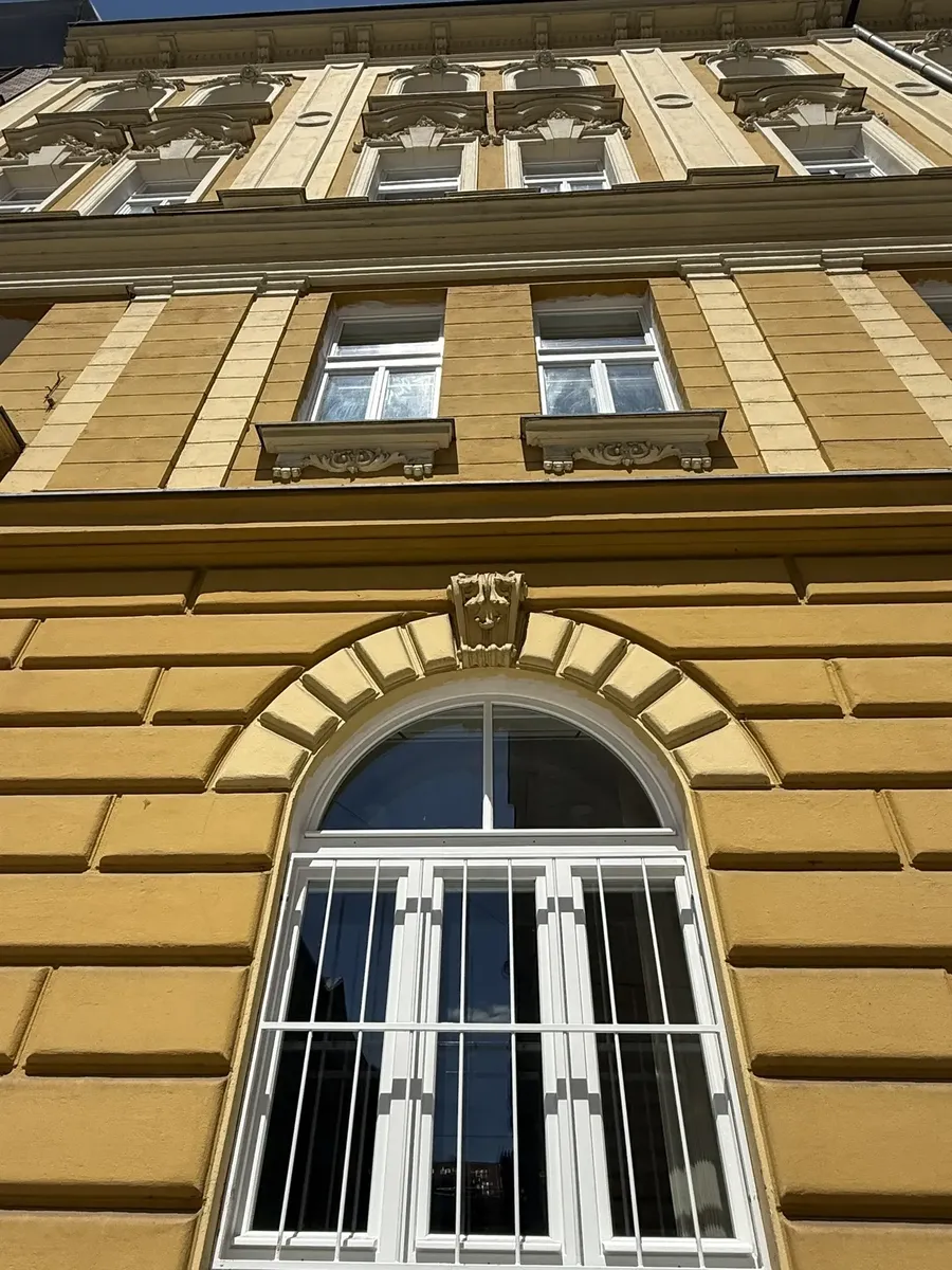 Bílá dřevěná okna na historické fasádě